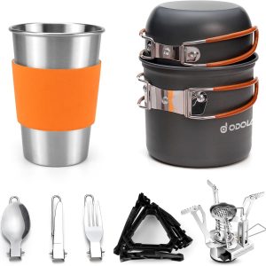 Odoland 12-in-1 camping cookware set with stainless steel cup, stove, tripod, and utensils on a picnic table